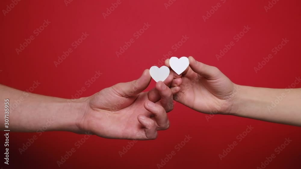 Close up of female and male hold in hands little white hearts isolated on red background. Valentines day and Like blogging blog social network tenderness concept. Close up of female and male hold in hands little white hearts isolated on red background. Valentines day and Like blogging blog social network tenderness concept.