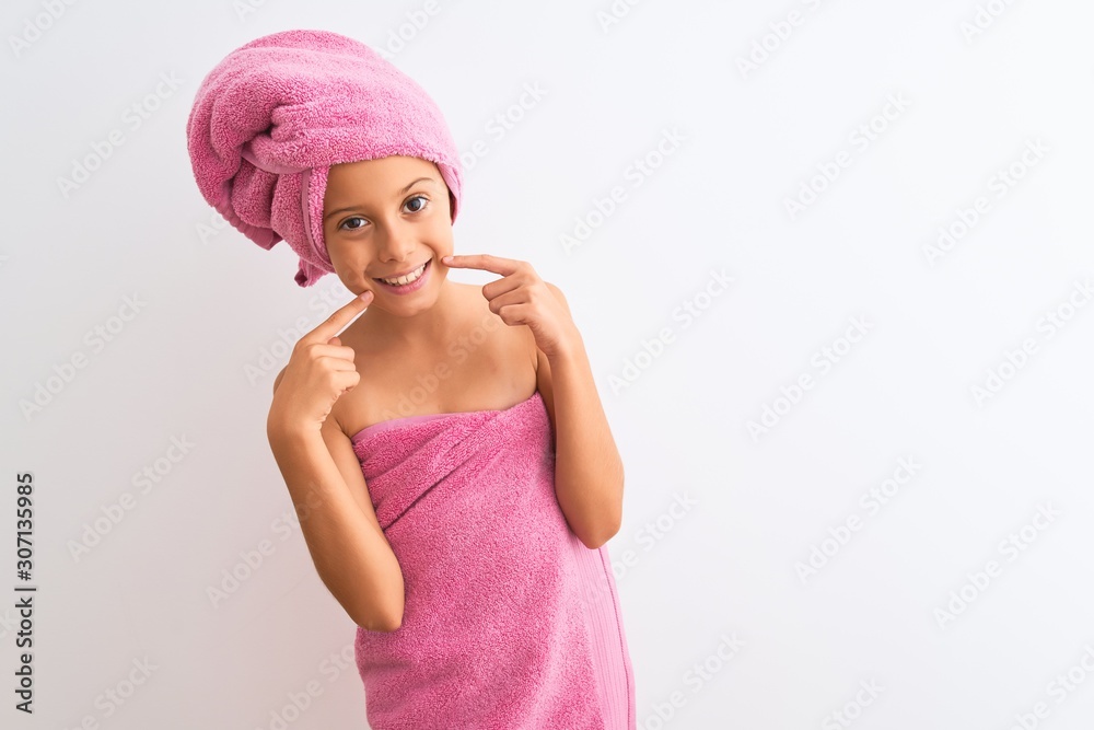 Beautiful child girl wearing shower towel after bath standing over isolated white background smiling cheerful showing and pointing with fingers teeth and mouth. Dental health concept. Beautiful child girl wearing shower towel after bath standing over isolated white background smiling cheerful showing and pointing with fingers teeth and mouth. Dental health concept.