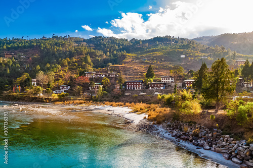 Mo Chhu River on a nice sunny day, Punakha, Bhutan. View from the wooden cantilever bridge near Punakha Dzong to river, houses of Punakha city and Himalaya mountains covered with forest. photo