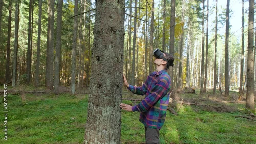 Young male with virtual reality glasses stand in the forest Young male with virtual reality glasses stand in the forest