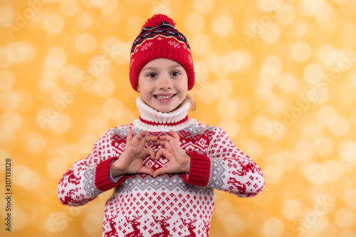 Little girl in winter look sputting her fingers in a heart shape