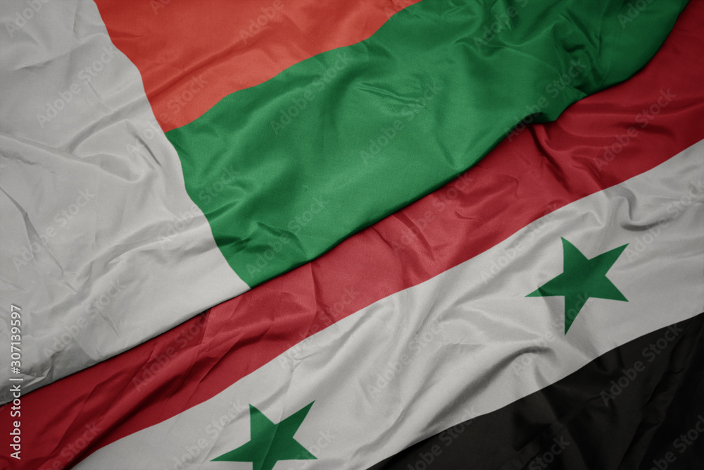Obraz premium waving colorful flag of syria and national flag of madagascar.
