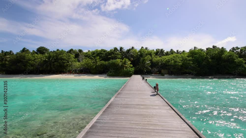 Shot of a fabulous island in the Maldives from a wooden pier. Cyan water, blue sky, sun, wooden pier. Shot of a fabulous island in the Maldives from a wooden pier. Cyan water, blue sky, sun, wooden pier.