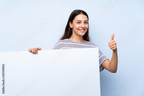 Young brunette woman over isolated blue background holding an empty white placard for insert a concept