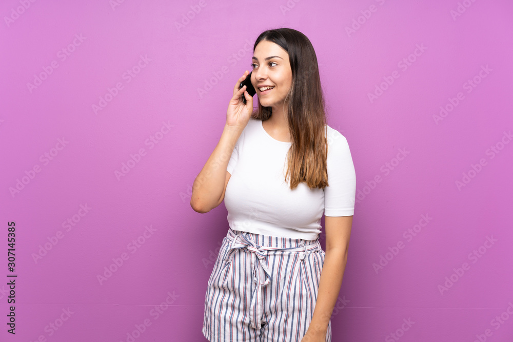 Young woman over isolated purple background keeping a conversation with the mobile phone Young woman over isolated purple background keeping a conversation with the mobile phone