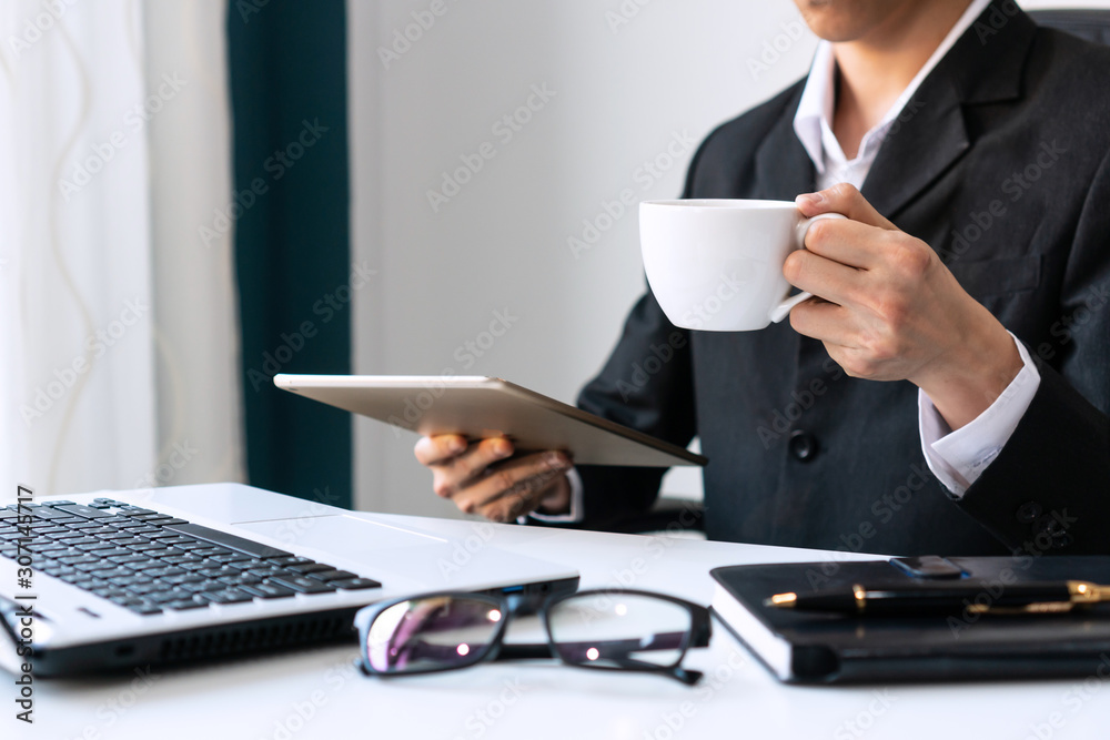 Businessman holding a white coffee cup and drink coffee in the morning while holding tablet. Businessman holding a white coffee cup and drink coffee in the morning while holding tablet.