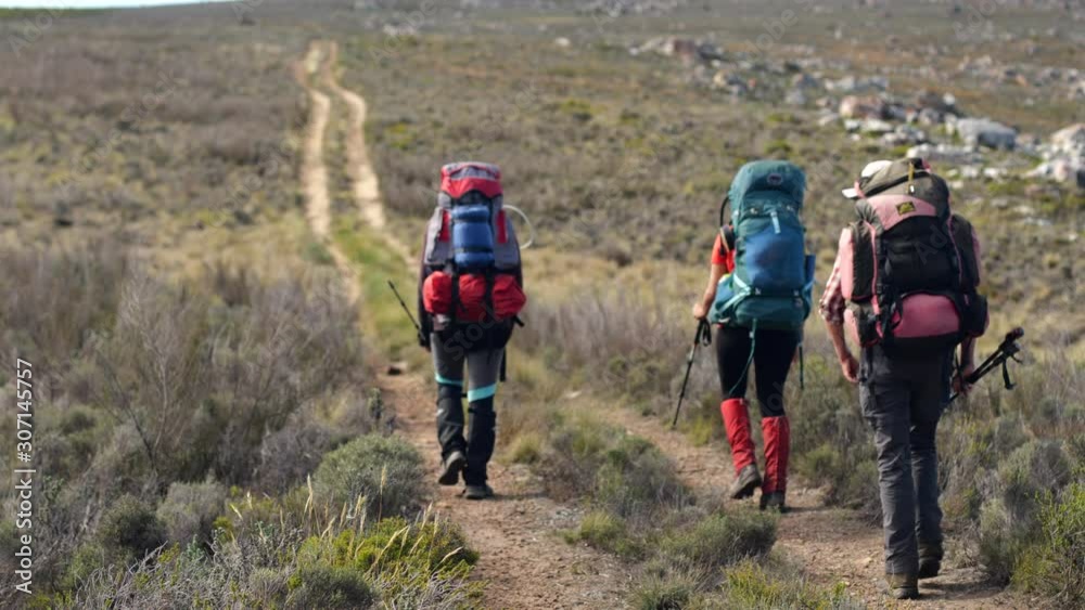 A group of hikers walking along an offroad car track in the outdoors. A group of hikers walking along an offroad car track in the outdoors.