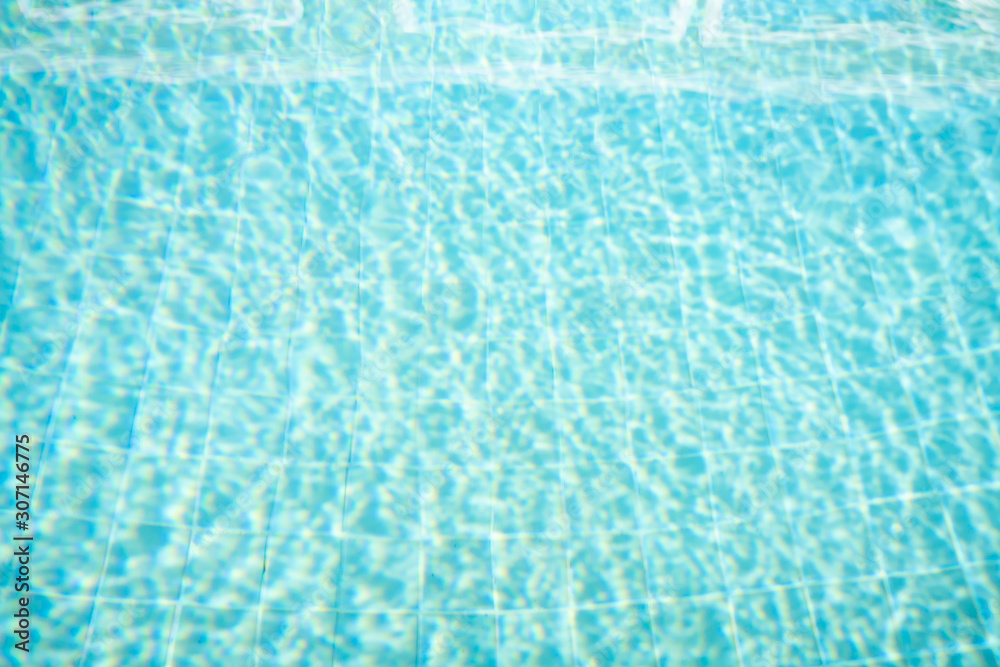Blurred photo of Top view Swimming pool bottom caustics ripple and flow with waves background.Summer background. Texture of water surface.Concept for chlorine in swimming pool water.