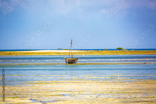 Fototapeta Old wooden boat in low water near coast of Zanzibar, tiny island in the backgrou