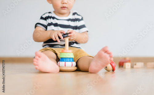 2.5 years baby boy.Little child boy playing stack with colorful wooden toys block alone.Kids play with educational toys at home.Day care and Kindergarten school.child development concept. photo