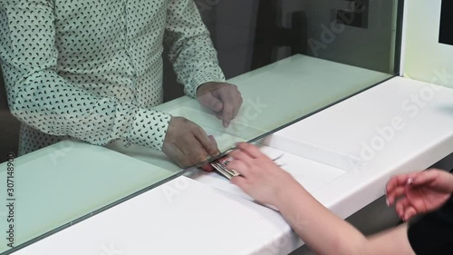 Employee and client count money on a counter at the currency exchange office. Female and male hand with money in cash department window.