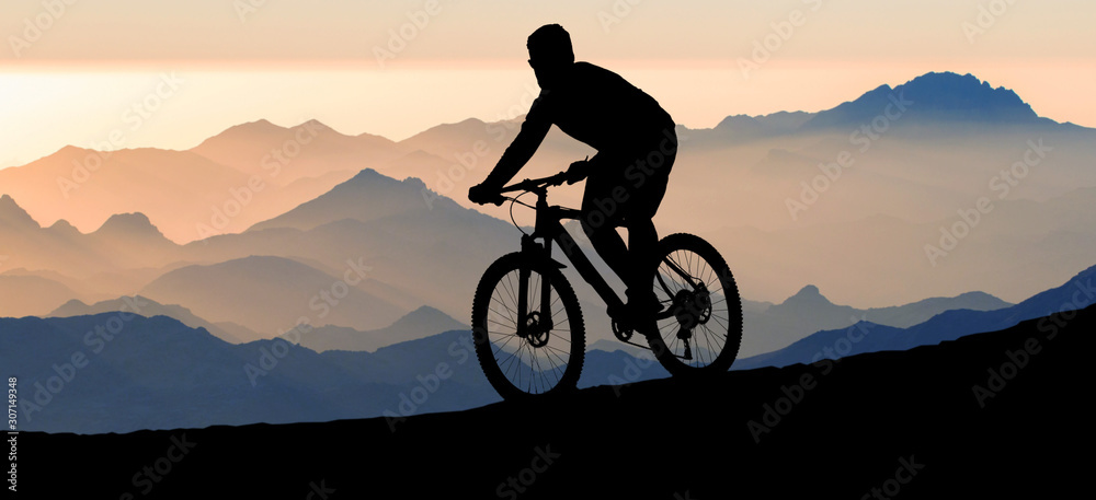 Cyclist in pants and fleece jacket on a modern carbon hardtail bike with an air suspension fork rides off-road.	