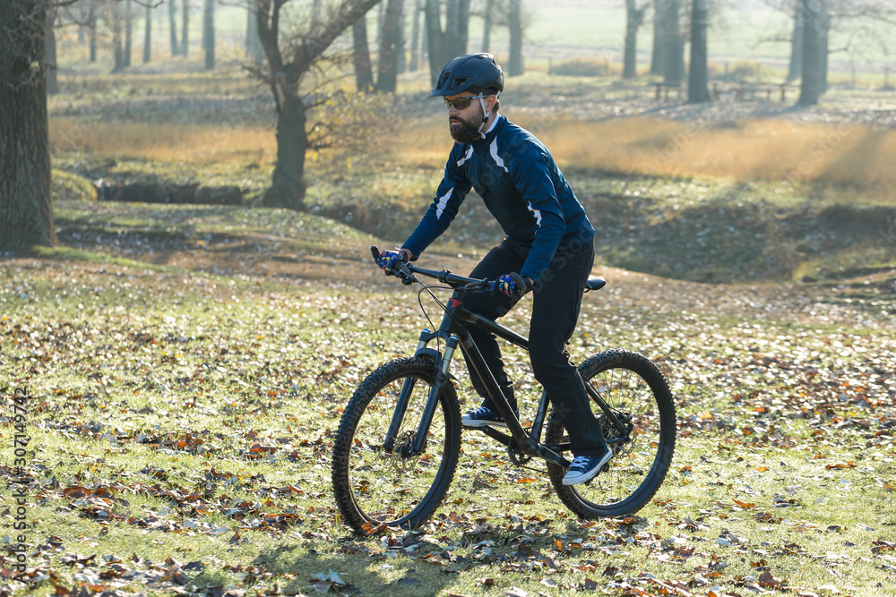 Fototapeta premium Cyclist in pants and fleece jacket on a modern carbon hardtail bike with an air suspension fork. The guy on the top of the hill rides a bike.