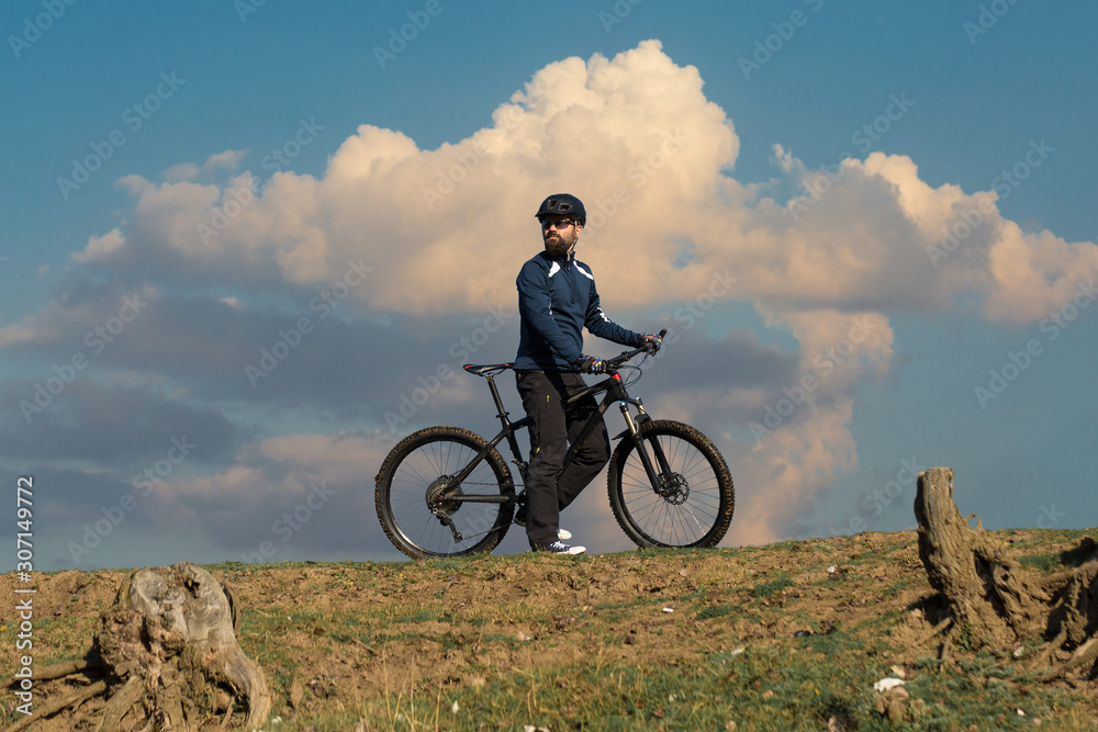 Fototapeta premium Cyclist in pants and fleece jacket on a modern carbon hardtail bike with an air suspension fork. The guy on the top of the hill rides a bike.