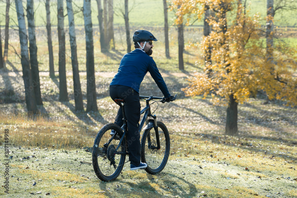 Cyclist in pants and fleece jacket on a modern carbon hardtail bike with an air suspension fork. The guy on the top of the hill rides a bike.