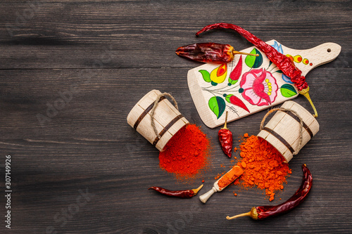 Magyar (Hungarian) red sweet and hot paprika powder. Traditional pattern on a cutting board, different varieties of dry pepper. Black wooden background photo