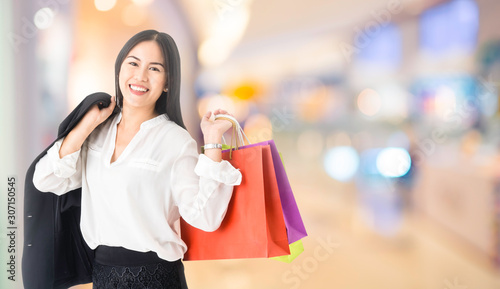 Happy office woman holding shopping bag on department store background.Girl shopping carrying shopping bags after shopping on the mall on Black friday sale.