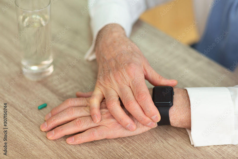 Senior Man's Hands Checking Smartwatch Before Taking A Pill, Cropped