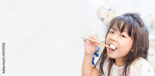 5.5 years old little asian girl teeth brushing with bamboo toothbrush.child girl smiling while brushing her teeth.brushing teeth, healthy oral care, zero wast and plastic free concept.copy space.