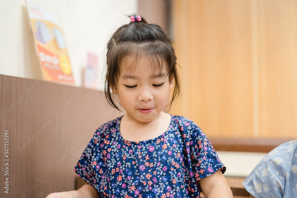 Happy positive funny little asian girl touching holding hands of full stomach.She eat over food and full with food in restaurant. Happy positive funny little asian girl touching holding hands of full stomach.She eat over food and full with food in restaurant.
