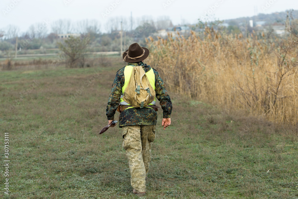 Hunting period, autumn season open. A hunter with a gun in his hands in hunting clothes in the autumn forest in search of a trophy. A man stands with weapons and hunting dogs tracking down the game. Hunting period, autumn season open. A hunter with a gun in his hands in hunting clothes in the autumn forest in search of a trophy. A man stands with weapons and hunting dogs tracking down the game.