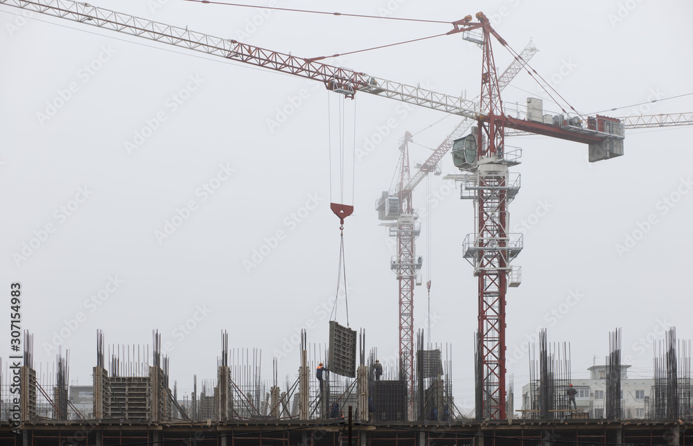 construction of a building with cranes in fog