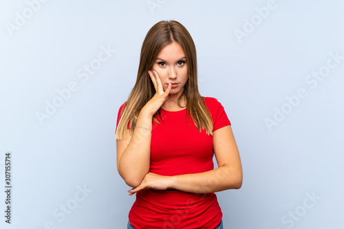Teenager girl over isolated blue background unhappy and frustrated