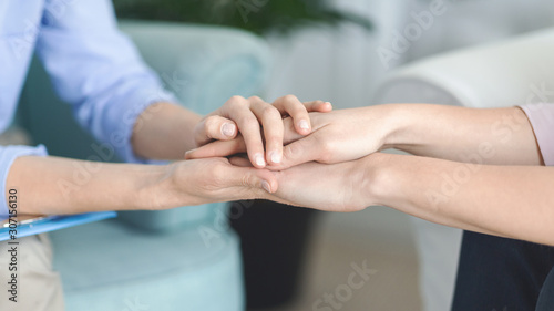 Psychologist consoling her client, holding her hands