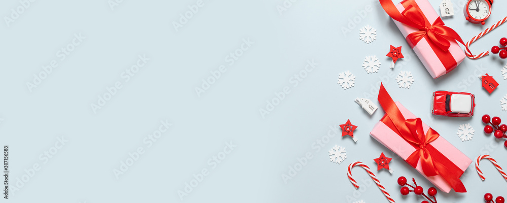 Merry Christmas and New Year congratulation card with pink paper boxes, red ribbons, glitter blur, car toy, stars and red berry on blue background Merry Christmas and New Year congratulation card with pink paper boxes, red ribbons, glitter blur, car toy, stars and red berry on blue background