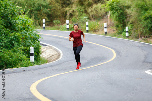 Front of woman runner and runing at the road surround with green forest.