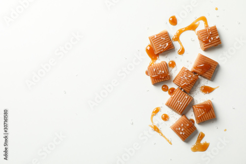 Tableau sur toile Salted caramel candies and sauce on white background, space for text