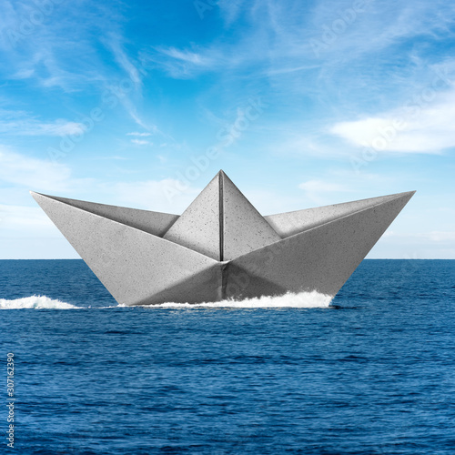 White paper boat runs fast over the blue sea with wake  sky with clouds on the background