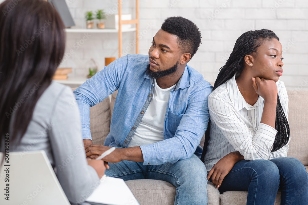 Indifferent black spouses sitting on couch at marital therapist's office. Indifferent black spouses sitting on couch at marital therapist's office.