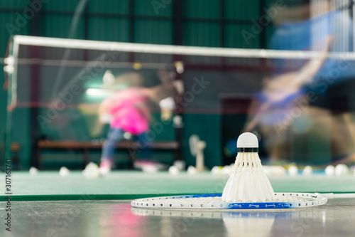 shuttlecock resting on a badminton racket with badminton player are competiting photo