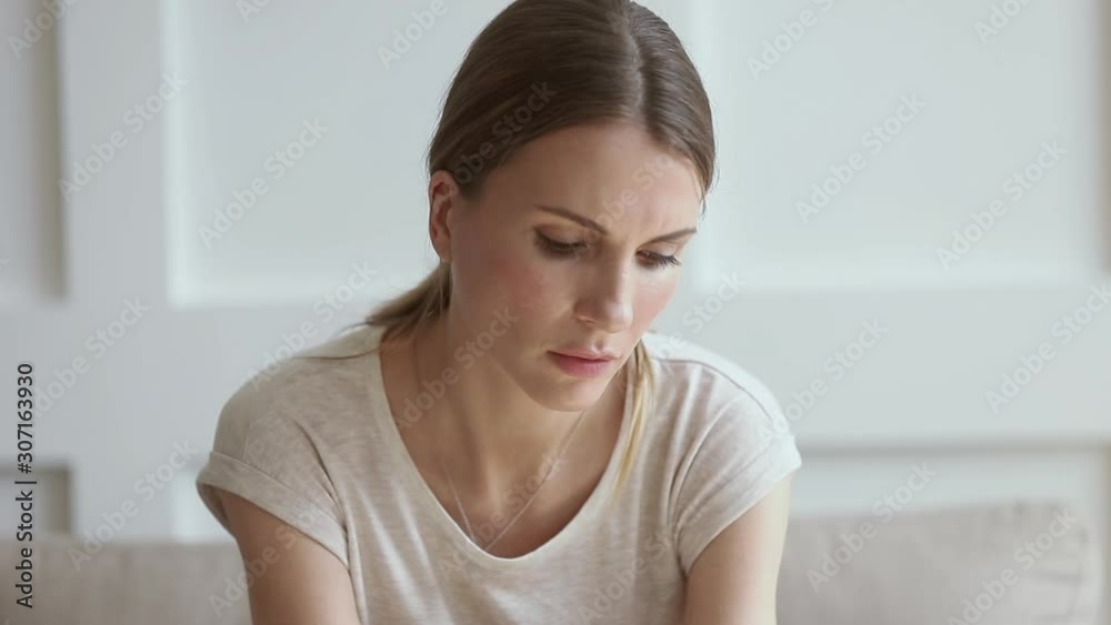 Unhappy young woman sitting alone on couch, lost in thoughts. Unhappy young woman sitting alone on couch, lost in thoughts.