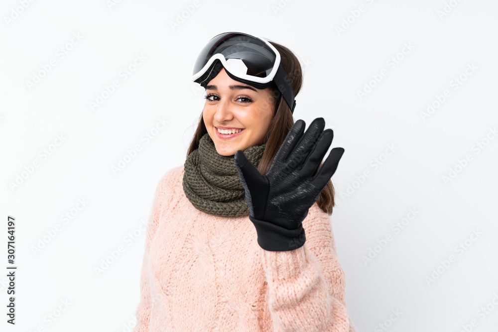 Skier girl with snowboarding glasses over isolated white wall saluting with hand with happy expression Skier girl with snowboarding glasses over isolated white wall saluting with hand with happy expression