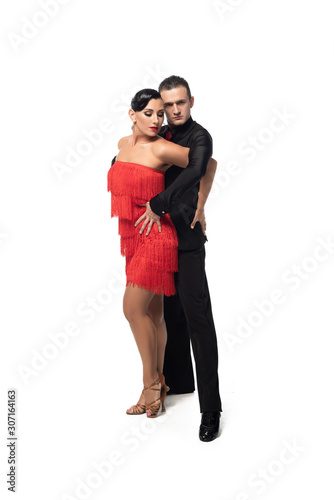 sensual dancer looking at camera while performing tango with attractive partner on white background