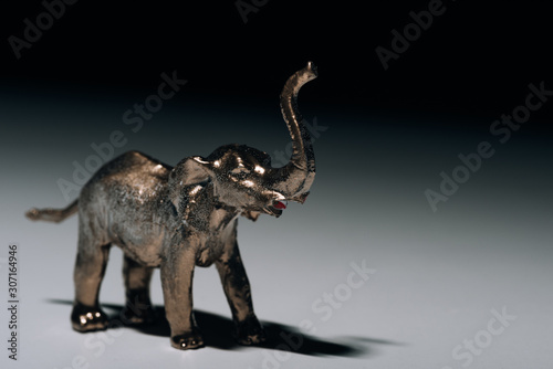 Golden toy elephant with blood on tusks on grey background, hunting for tusks concept © LIGHTFIELD STUDIOS