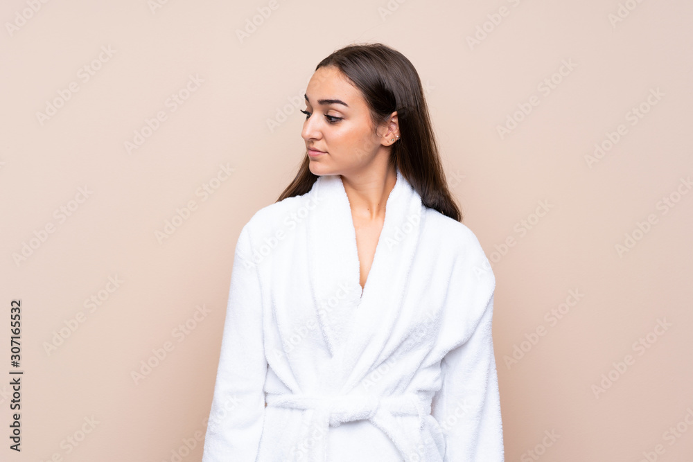 Young girl in a bathrobe over isolated background looking side Young girl in a bathrobe over isolated background looking side