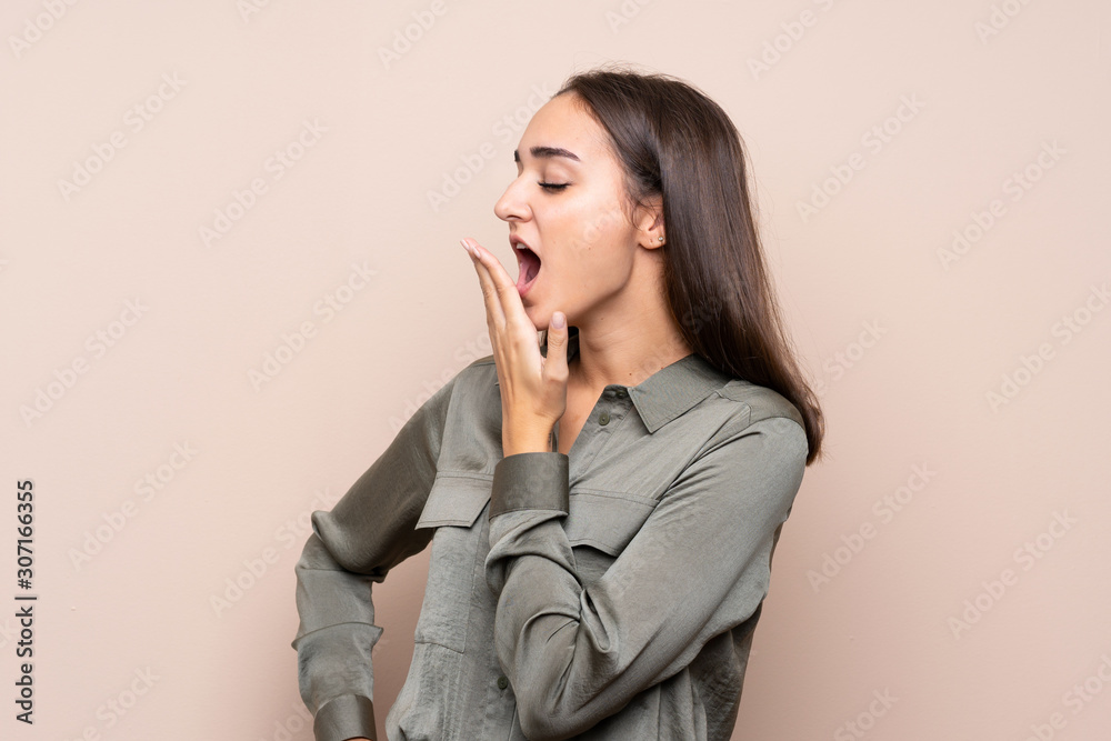 Young girl over isolated background yawning and covering wide open mouth with hand