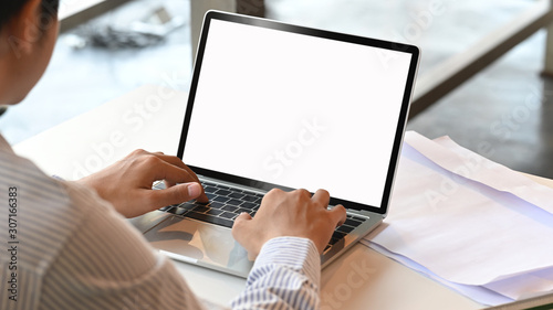 Cropped shot man typing mockup laptop computer with blank screen.
