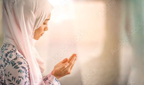 Young beautiful muslim women open palm  peaceful praying in mosque.