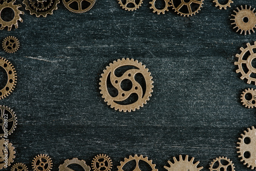 top view of vintage metal gears arranged in frame on dark wooden background © LIGHTFIELD STUDIOS