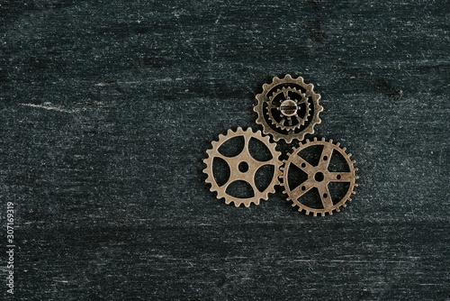 top view of vintage metal gears on dark wooden background with copy space © LIGHTFIELD STUDIOS