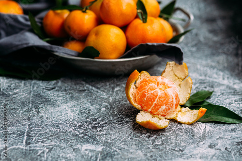  Ripe tangerines in a plate on a gray table