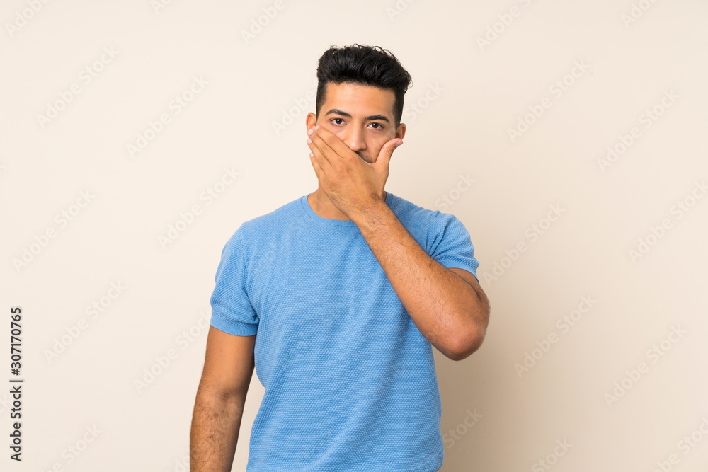 Young handsome man over isolated background covering mouth with hands Young handsome man over isolated background covering mouth with hands