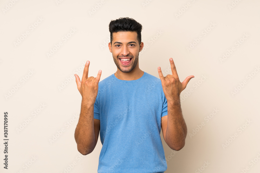 Young handsome man over isolated background making rock gesture Young handsome man over isolated background making rock gesture