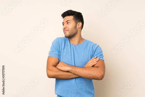 Young handsome man over isolated background making doubts gesture while lifting the shoulders