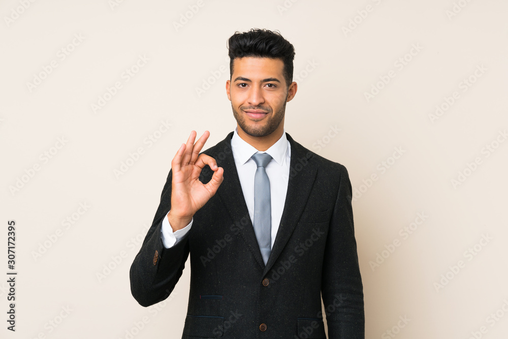 Young handsome businessman man over isolated background showing an ok sign with fingers