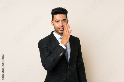 Young handsome businessman man over isolated background whispering something